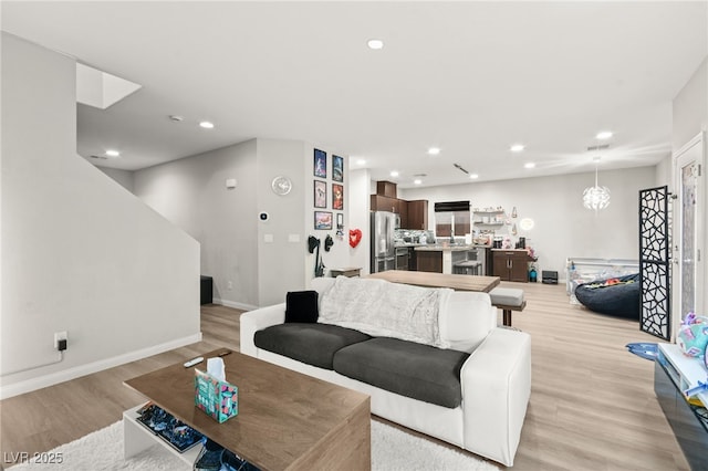 living area with baseboards, recessed lighting, and light wood-style floors