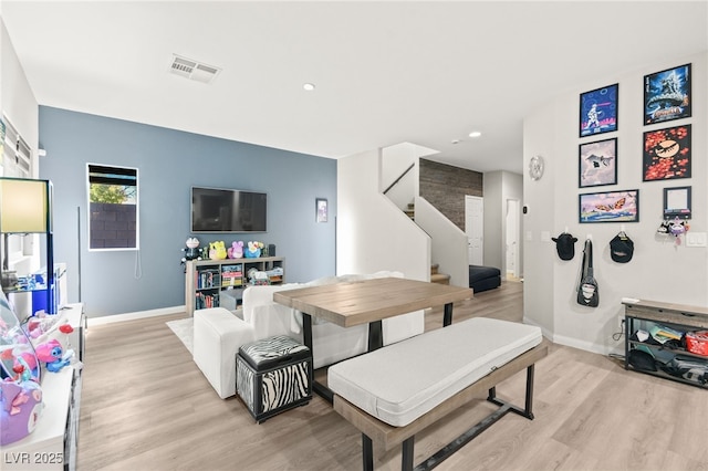 living area with light wood-style flooring, stairway, visible vents, and baseboards