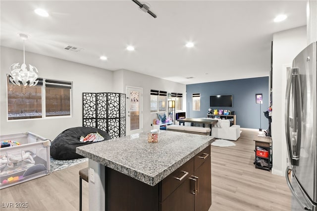 kitchen with freestanding refrigerator, open floor plan, a center island, and dark brown cabinets