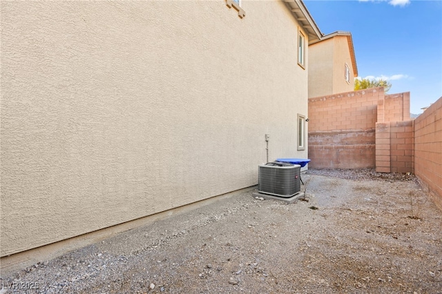 view of home's exterior with a fenced backyard, central AC, and stucco siding