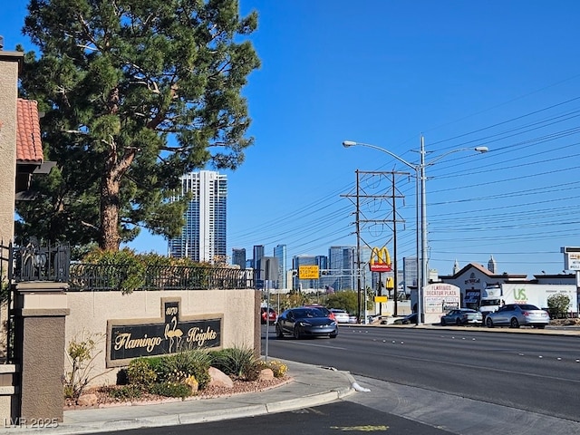 view of street with street lights, curbs, sidewalks, and a city view