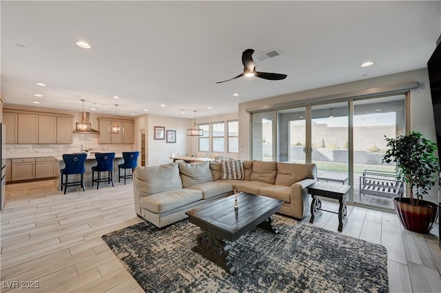 living room with light wood-type flooring, ceiling fan, visible vents, and recessed lighting