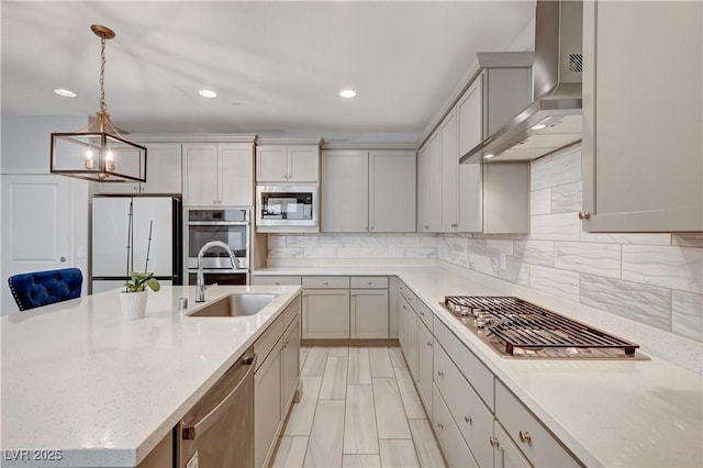 kitchen featuring stainless steel appliances, hanging light fixtures, backsplash, a sink, and wall chimney exhaust hood