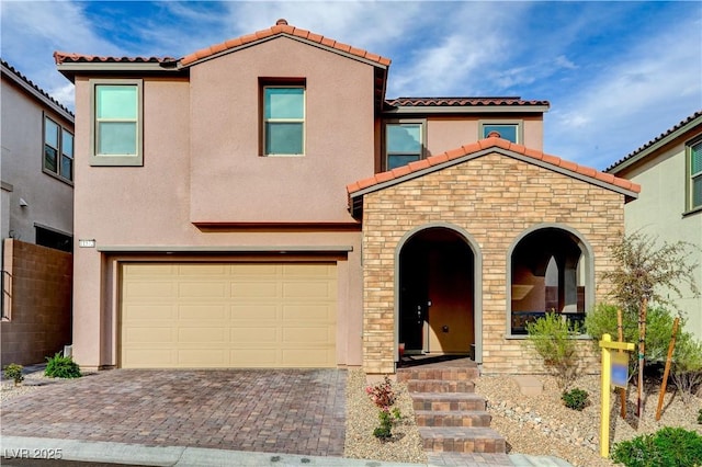 mediterranean / spanish home with stone siding, a tile roof, an attached garage, decorative driveway, and stucco siding