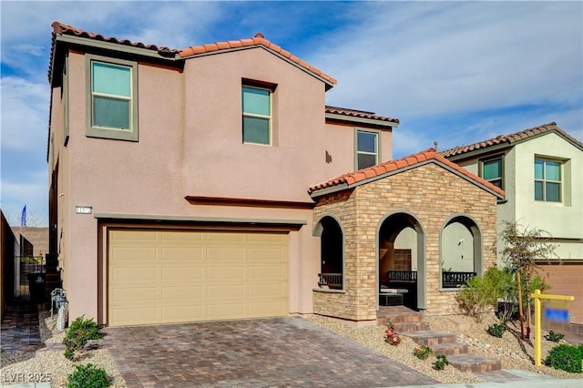 mediterranean / spanish-style house featuring a garage, stone siding, decorative driveway, and stucco siding