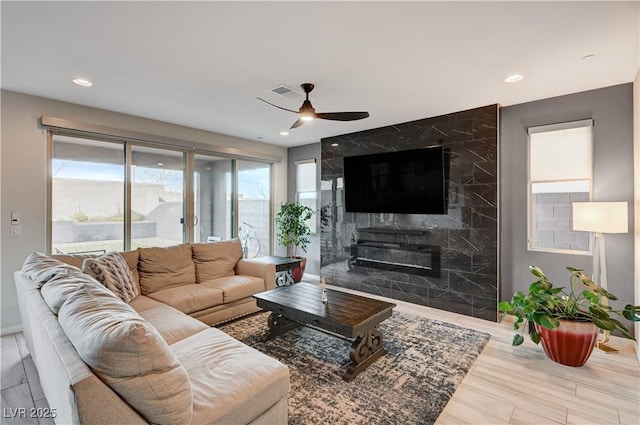 living area with ceiling fan, recessed lighting, a premium fireplace, wood finished floors, and visible vents