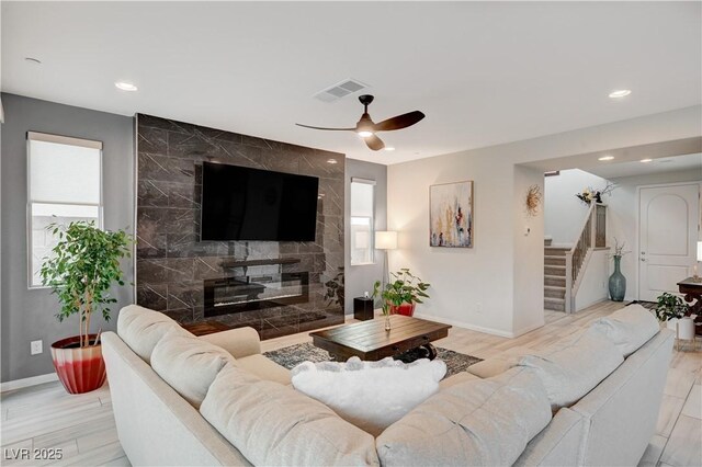 living area with visible vents, stairway, baseboards, and a premium fireplace