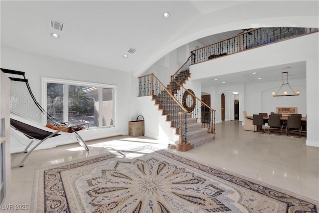 foyer featuring visible vents, arched walkways, stairway, high vaulted ceiling, and a notable chandelier