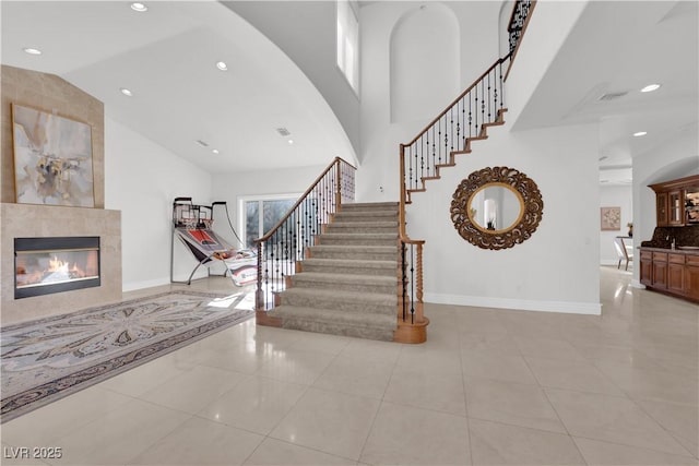 entrance foyer with high vaulted ceiling, stairs, baseboards, and a tiled fireplace