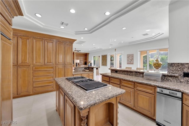 kitchen featuring recessed lighting, a peninsula, a kitchen island, light stone countertops, and stainless steel gas stovetop