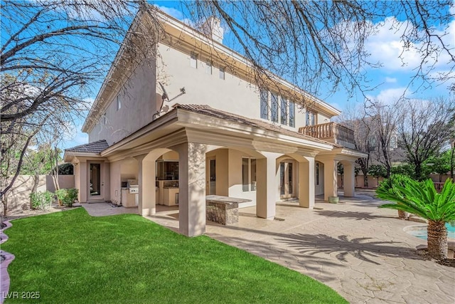 back of property with a lawn, a patio, a balcony, fence, and stucco siding