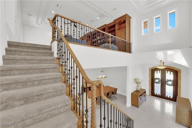 staircase with french doors, a towering ceiling, and recessed lighting