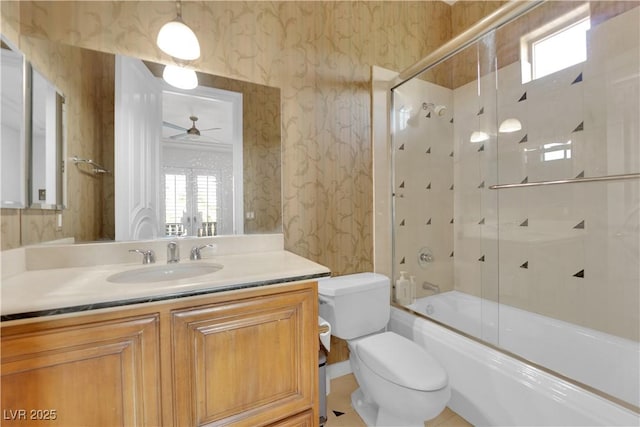 full bath with shower / bath combination with glass door, toilet, ceiling fan, vanity, and wallpapered walls