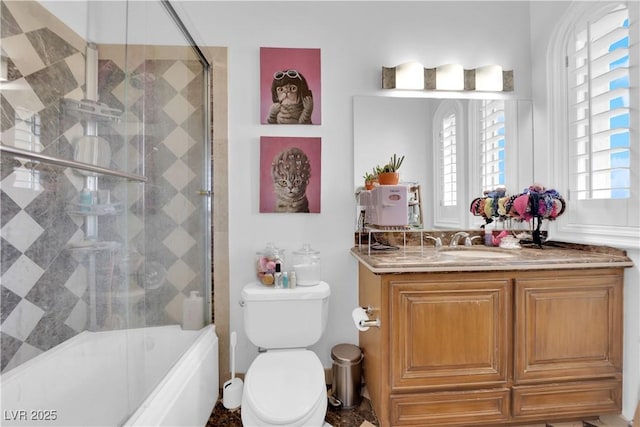 bathroom with combined bath / shower with glass door, vanity, and toilet