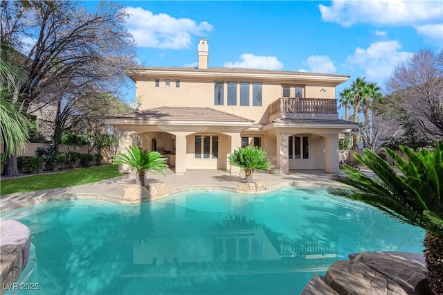 rear view of property featuring a fenced in pool, a patio, a balcony, and stucco siding