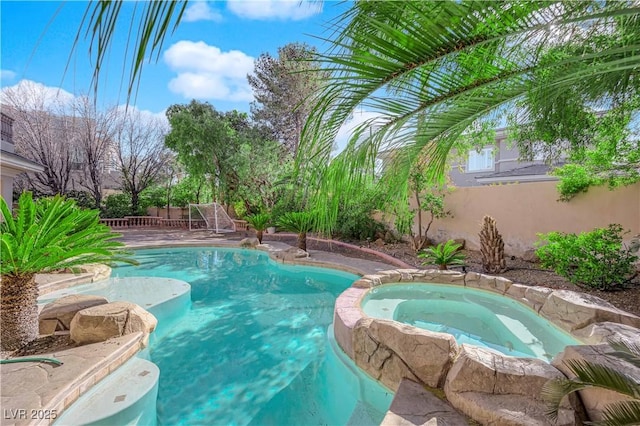 view of pool with a pool with connected hot tub and fence