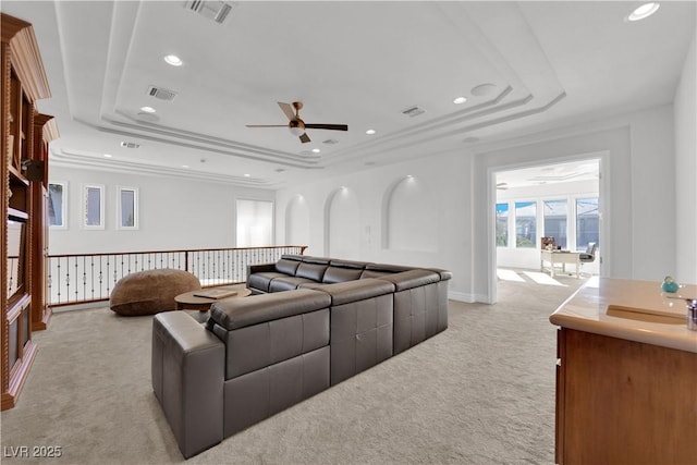 living room with light carpet, visible vents, and a raised ceiling