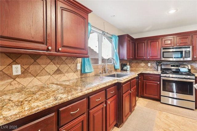 kitchen with stainless steel appliances, a sink, dark brown cabinets, light stone countertops, and tasteful backsplash