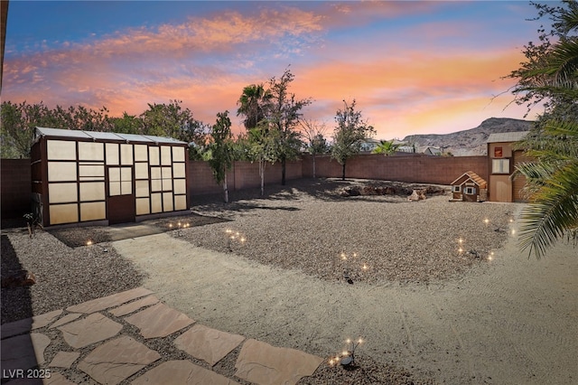 view of yard with a fenced backyard, a mountain view, and an outbuilding