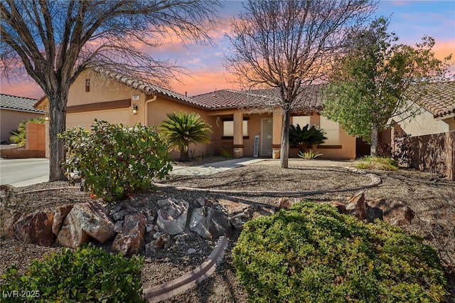 view of front of home featuring a garage, a tile roof, concrete driveway, and stucco siding