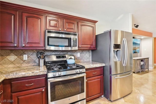 kitchen featuring appliances with stainless steel finishes, dark brown cabinets, decorative backsplash, and light stone counters