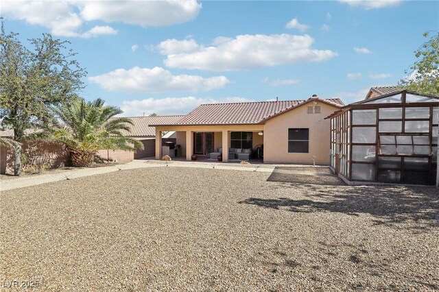 rear view of property with a patio, a tile roof, fence, and stucco siding