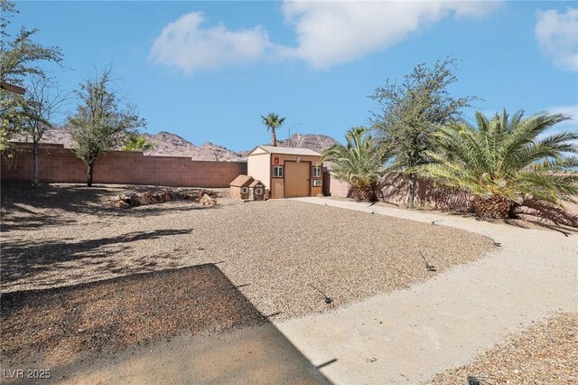 view of yard featuring an outbuilding, a storage shed, a mountain view, a garage, and a fenced backyard