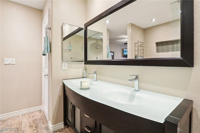 full bath with double vanity, a closet, a sink, wood finished floors, and baseboards