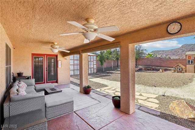 view of patio / terrace with a mountain view, an outdoor living space, a fenced backyard, and a ceiling fan