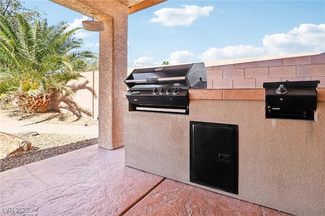 view of patio / terrace with grilling area, fence, and an outdoor kitchen