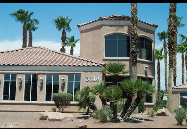 back of property with a tiled roof and stucco siding