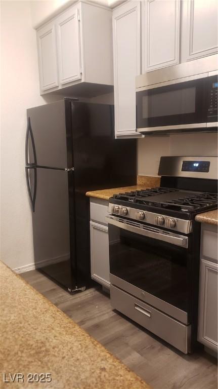 kitchen with appliances with stainless steel finishes, light countertops, light wood-style floors, and white cabinetry