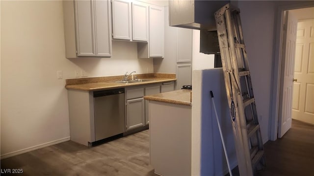 kitchen featuring light wood-style flooring, a sink, baseboards, light countertops, and stainless steel dishwasher