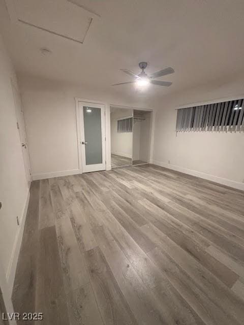 interior space with attic access, ceiling fan, baseboards, and wood finished floors