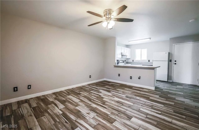 interior space featuring dark wood-type flooring, a sink, baseboards, and a ceiling fan