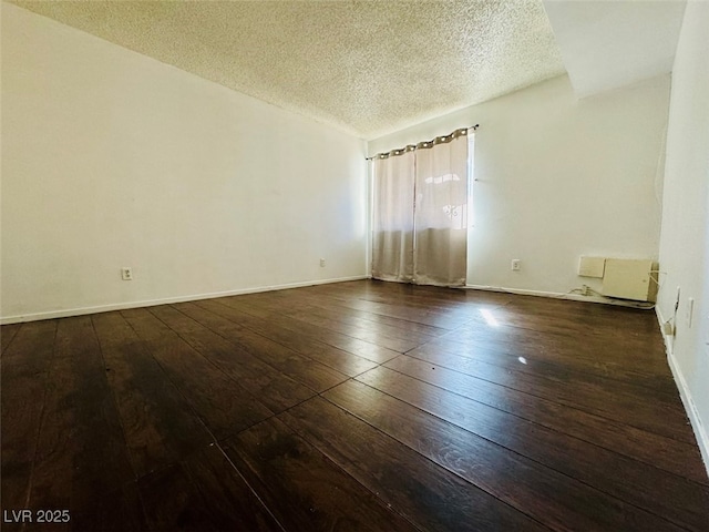 unfurnished room featuring a textured ceiling, dark wood-type flooring, lofted ceiling, and baseboards