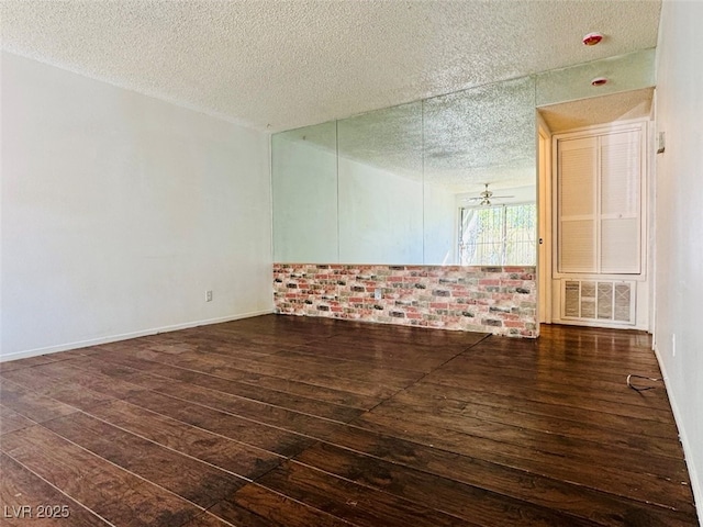 unfurnished room featuring baseboards, visible vents, a ceiling fan, dark wood-type flooring, and a textured ceiling