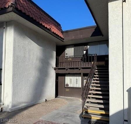 property entrance with a tile roof and stucco siding