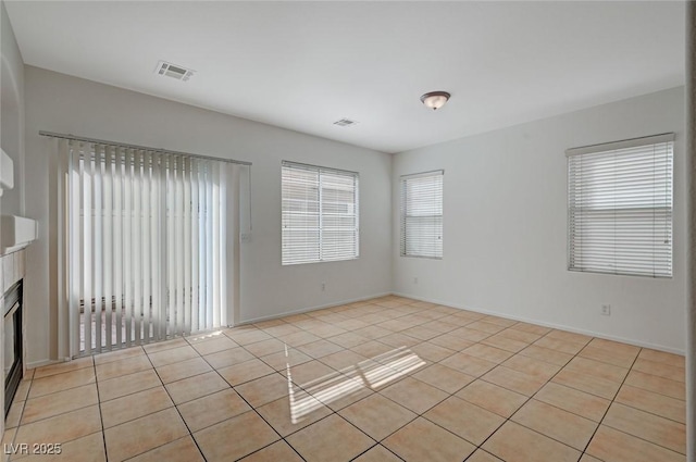 spare room with visible vents, a fireplace, and light tile patterned floors