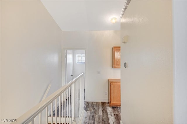 hallway with an upstairs landing, baseboards, and light wood finished floors