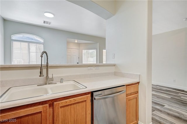 kitchen featuring visible vents, wood finished floors, light countertops, stainless steel dishwasher, and a sink