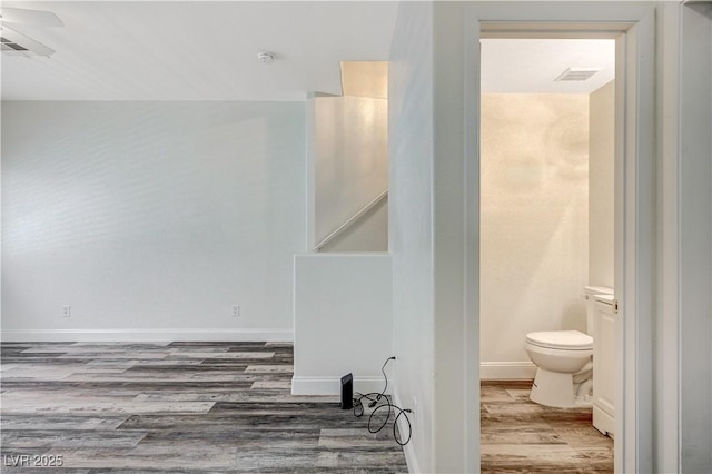 bathroom featuring toilet, visible vents, baseboards, and wood finished floors