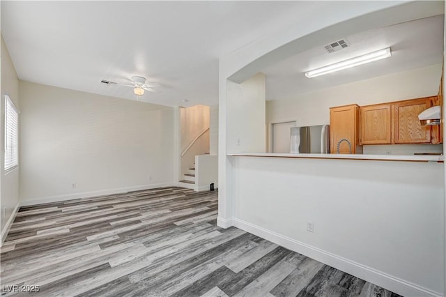 unfurnished room featuring baseboards, stairs, visible vents, and wood finished floors