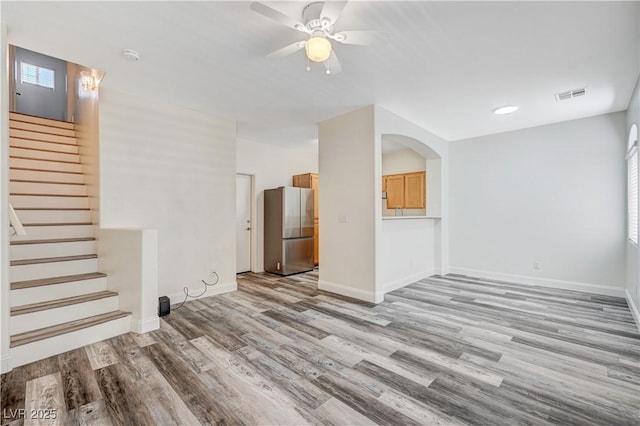 unfurnished living room featuring wood finished floors, visible vents, baseboards, and stairs