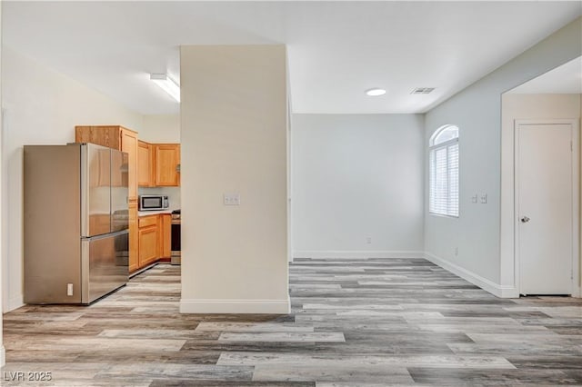 kitchen with light wood finished floors, baseboards, visible vents, and stainless steel appliances