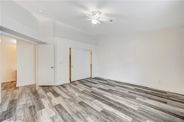 unfurnished bedroom featuring a closet, wood finished floors, a ceiling fan, and baseboards