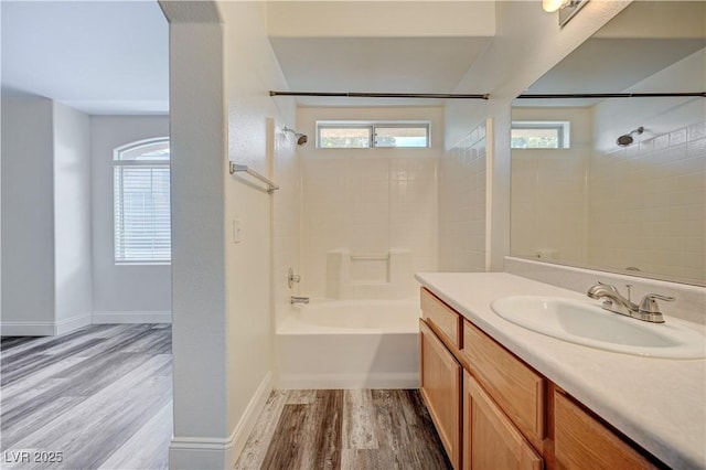 bathroom with a wealth of natural light, tub / shower combination, vanity, and wood finished floors