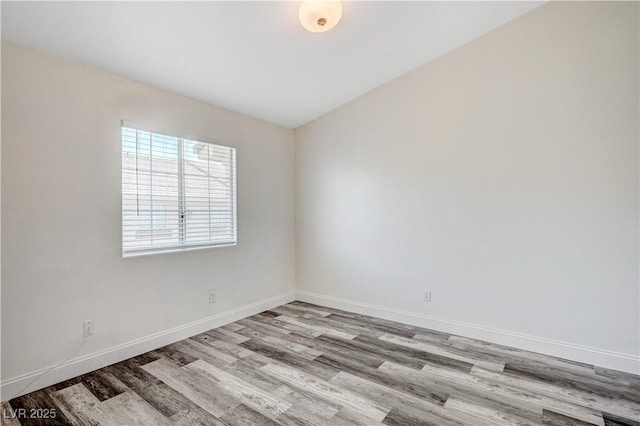 spare room with baseboards and wood finished floors