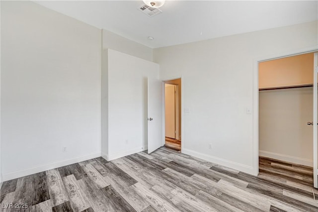 unfurnished bedroom featuring a closet, visible vents, baseboards, and wood finished floors