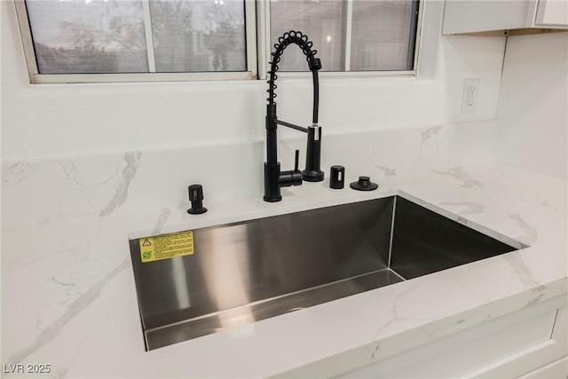 interior details with light stone counters, white cabinetry, and a sink